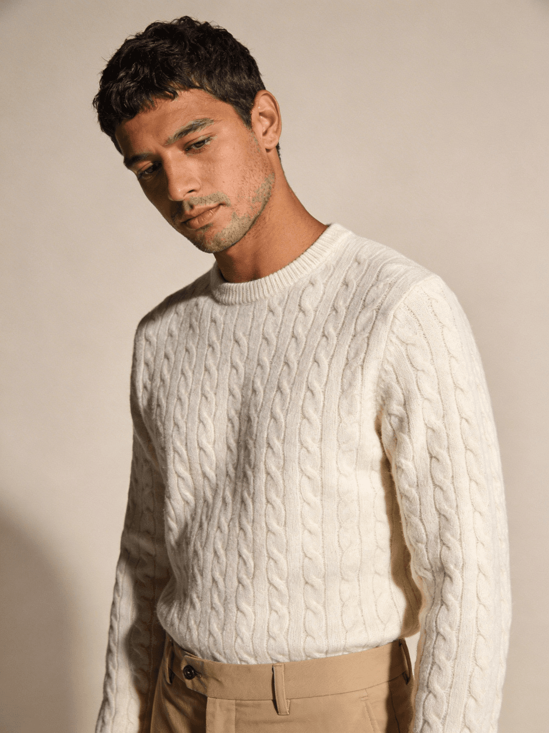 Model in an ecru cable-knit sweater and camel trousers