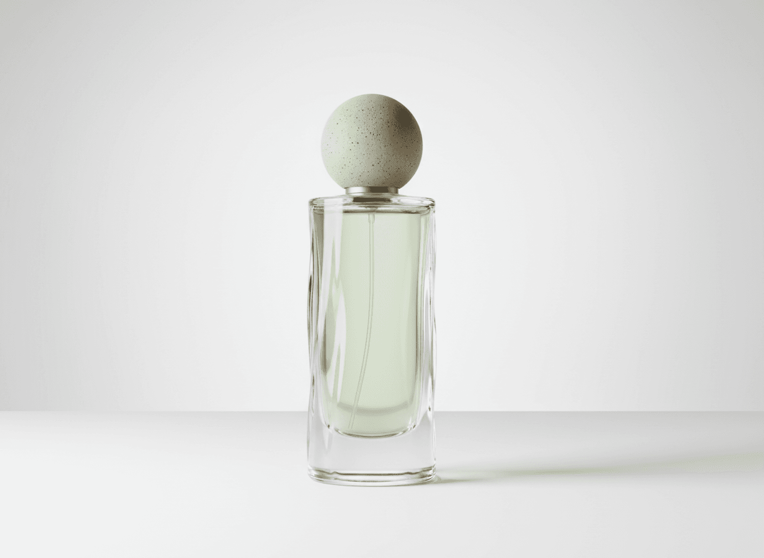 Tall glass perfume bottle with pale green juice and a round stone stopper